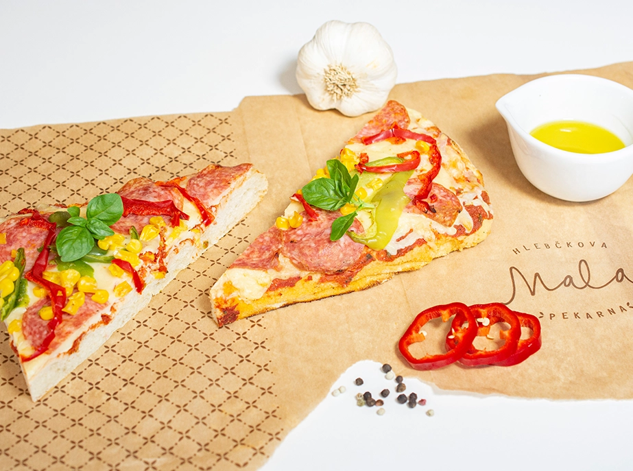 Dva koščka pizza trikotnikov na mizi lepo aranžirana z oljem, česnom in papriko